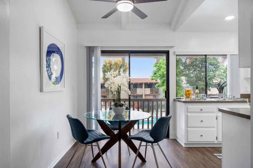 a dining room with a glass table and chairs and a window