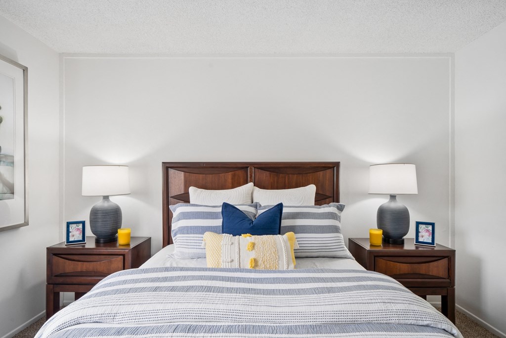 a bedroom with a bed with blue and white pillows and a wooden headboard