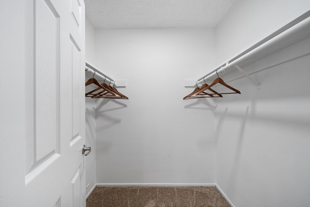a walk in closet with two hanging racks and a white door