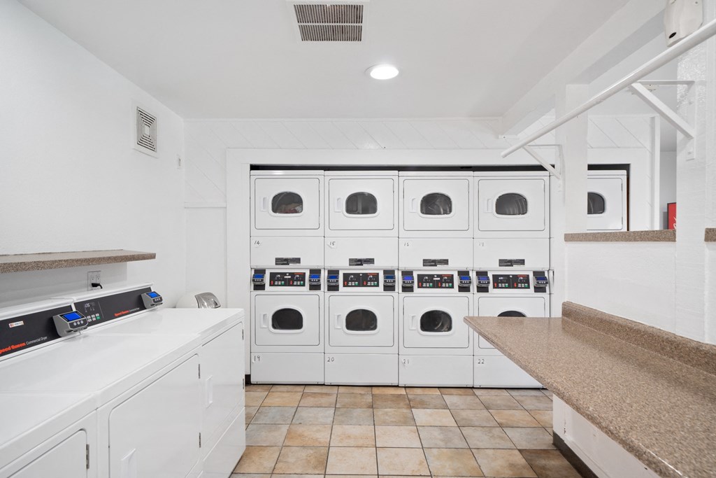 a laundry room with white cabinets and a row of white washing machines