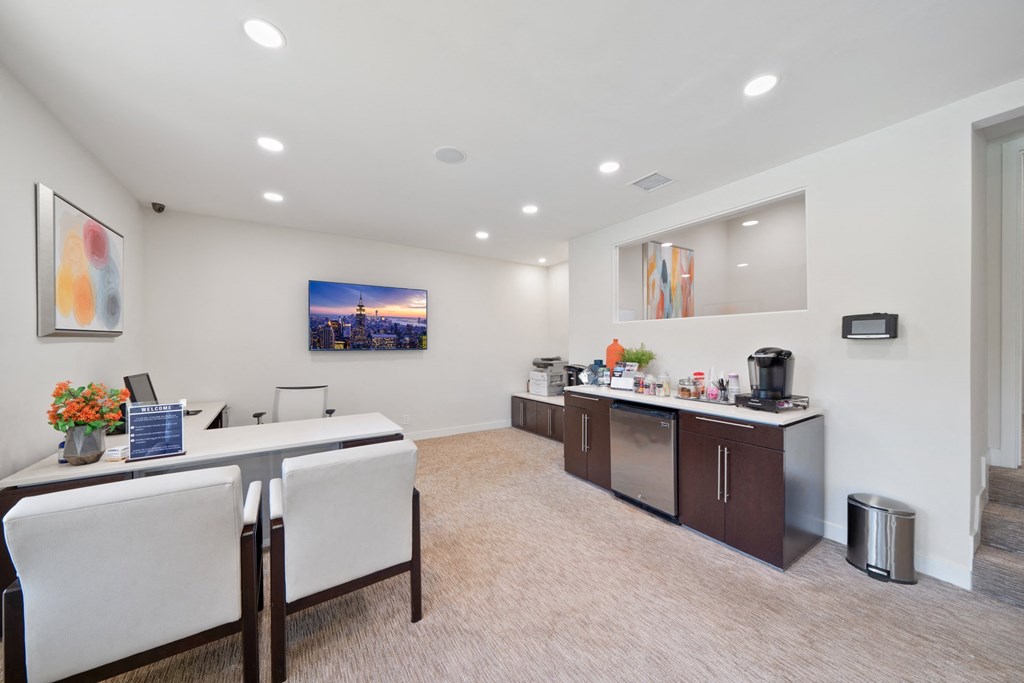 a conference room with two desks and chairs and a counter with a sink