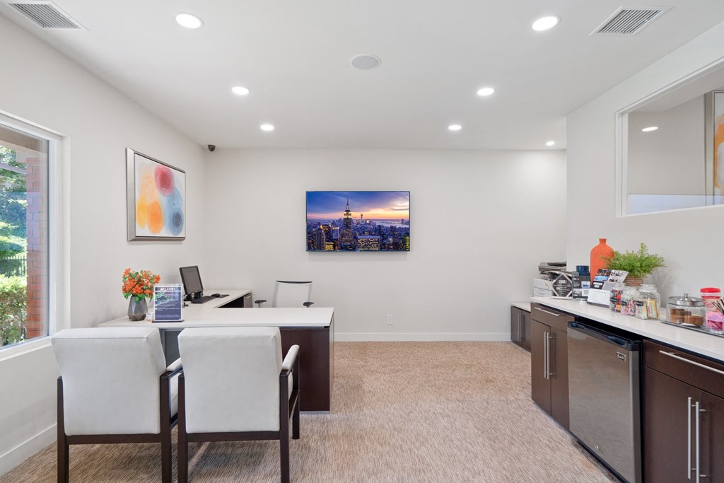 a white office with a desk and chairs and a window