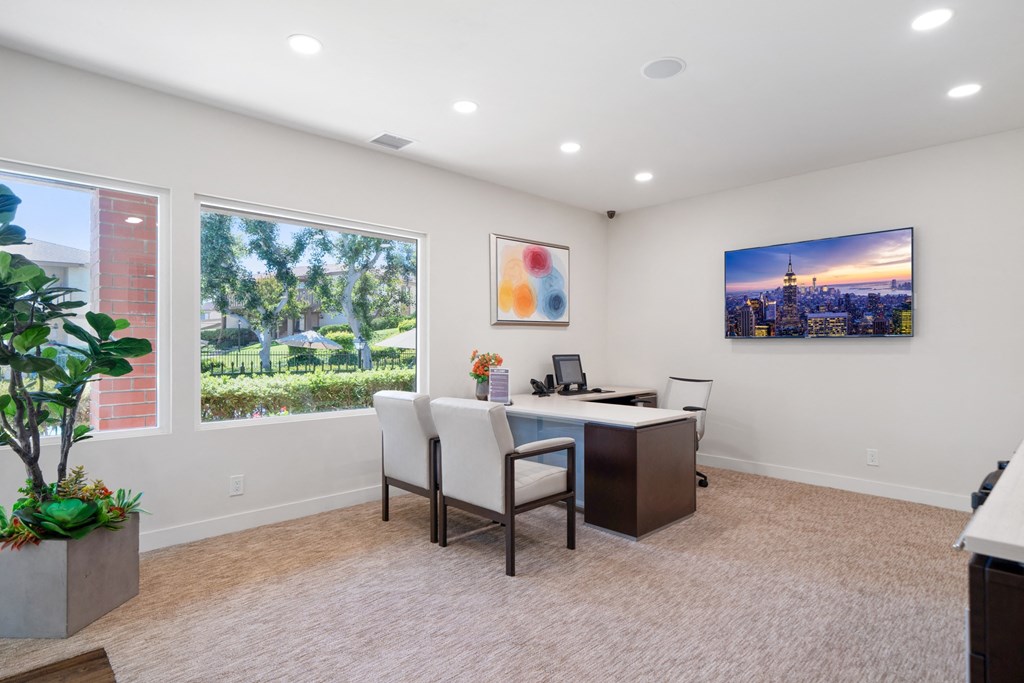 an office with a desk and chairs and a large window