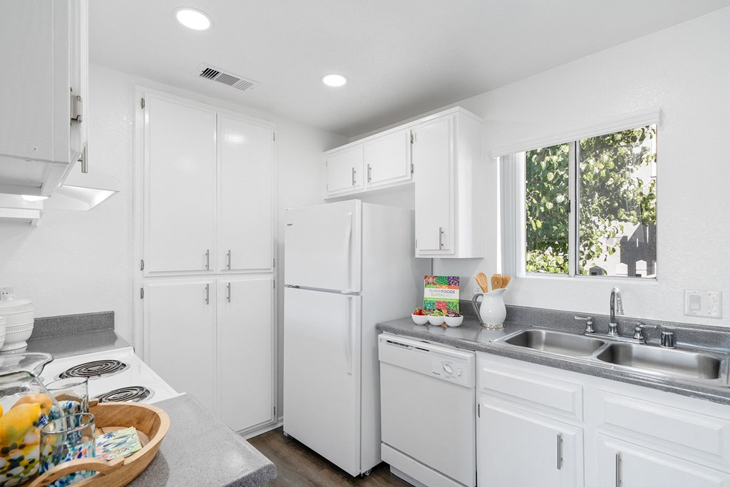 a kitchen with white cabinets and a sink and a refrigerator