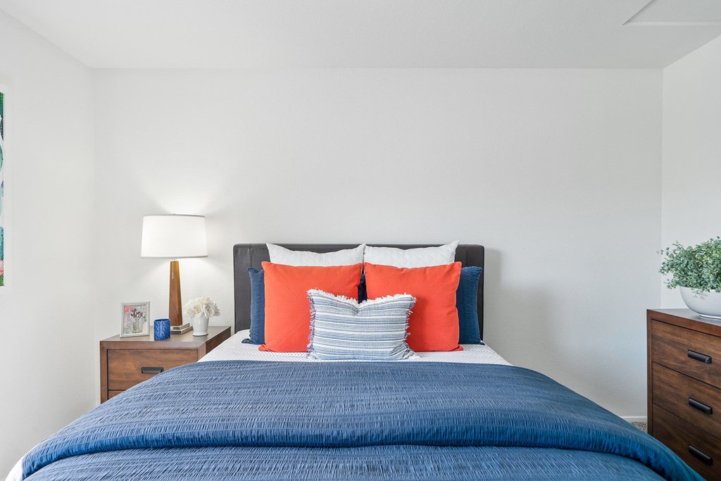 a bedroom with a blue bed and orange and blue pillows