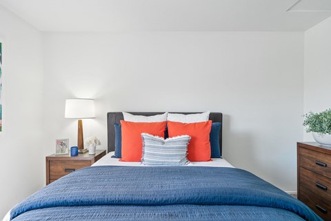 a bedroom with a blue bed and orange and blue pillows