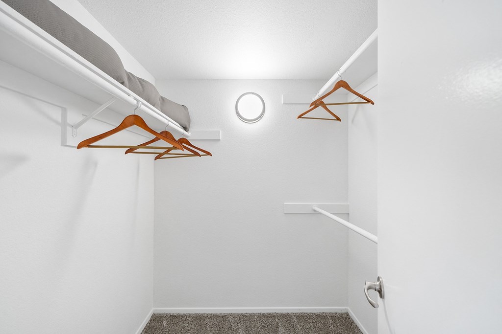 an empty closet with clothes hangers in a white room