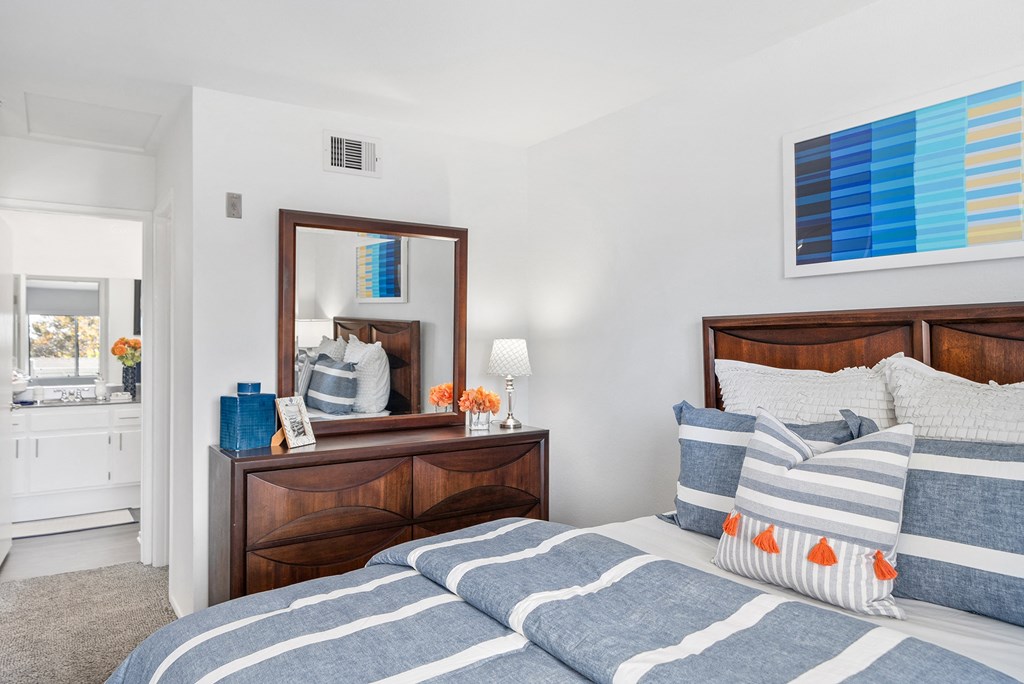 a bedroom with a bed and a mirror and a bathroom