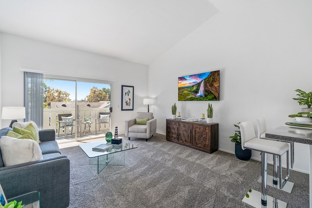 a living room with white walls and a sliding glass door to a balcony