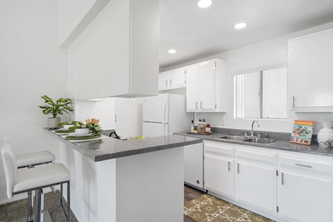 a white kitchen with white cabinets and a gray counter top