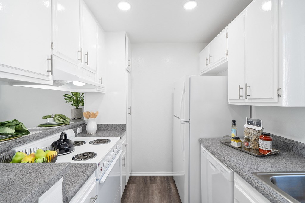 a white kitchen with white appliances and granite counter tops