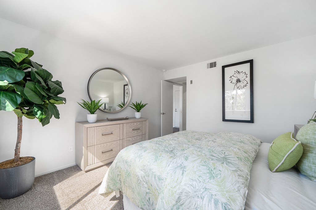 a bedroom with a bed and a mirror and a plant
