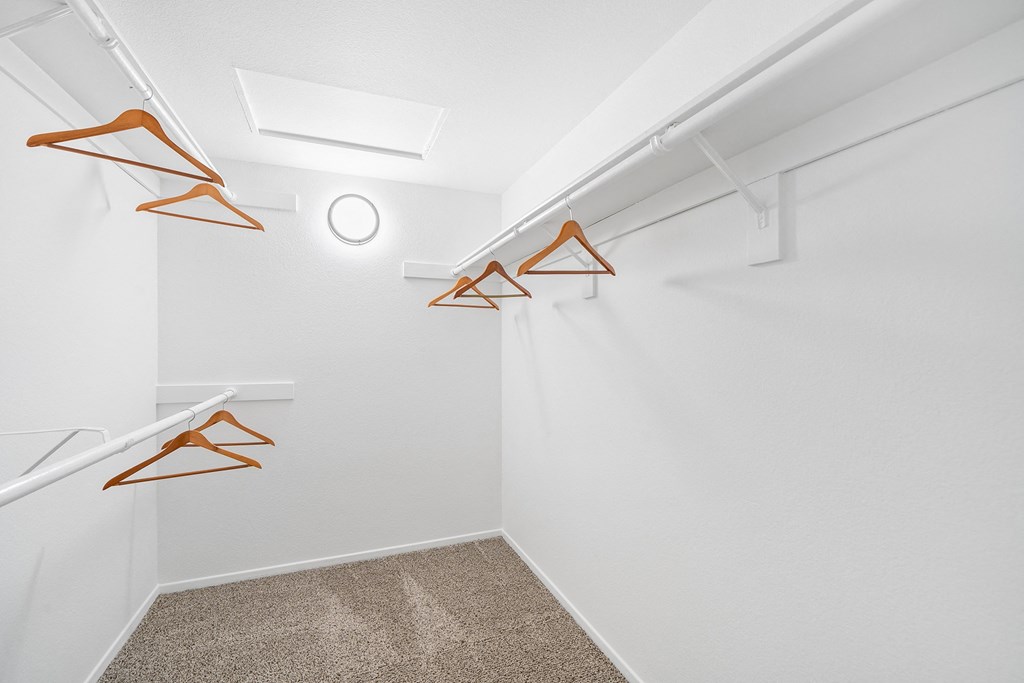 the interior of a white closet with white walls and orange hooks