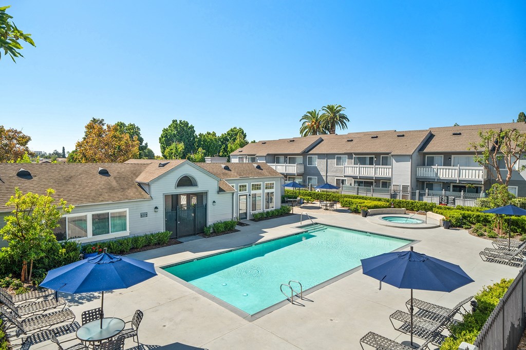a swimming pool with umbrellas and apartments in the background