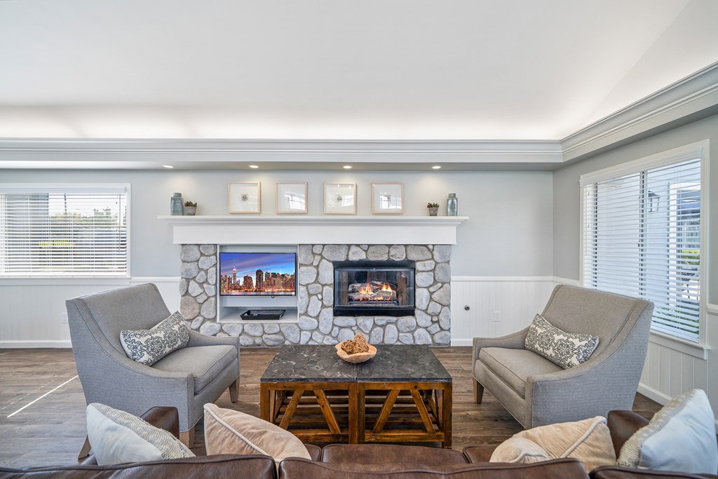 a living room with a stone fireplace and chairs and a table