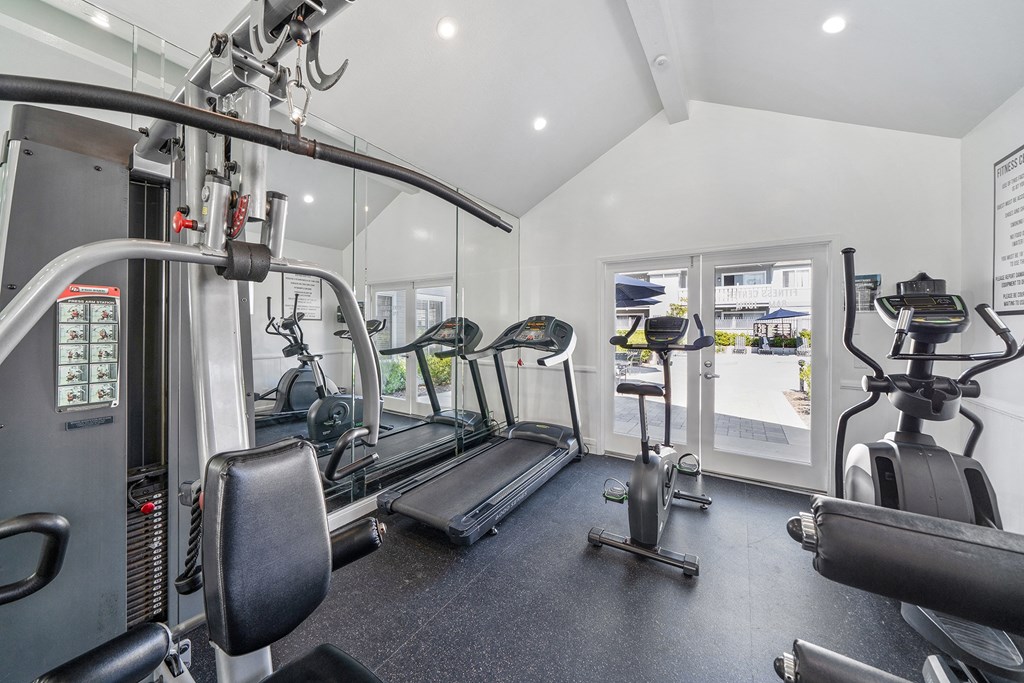 a gym with cardio equipment and weights on the floor