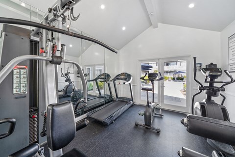 a gym with cardio equipment and weights on the floor
