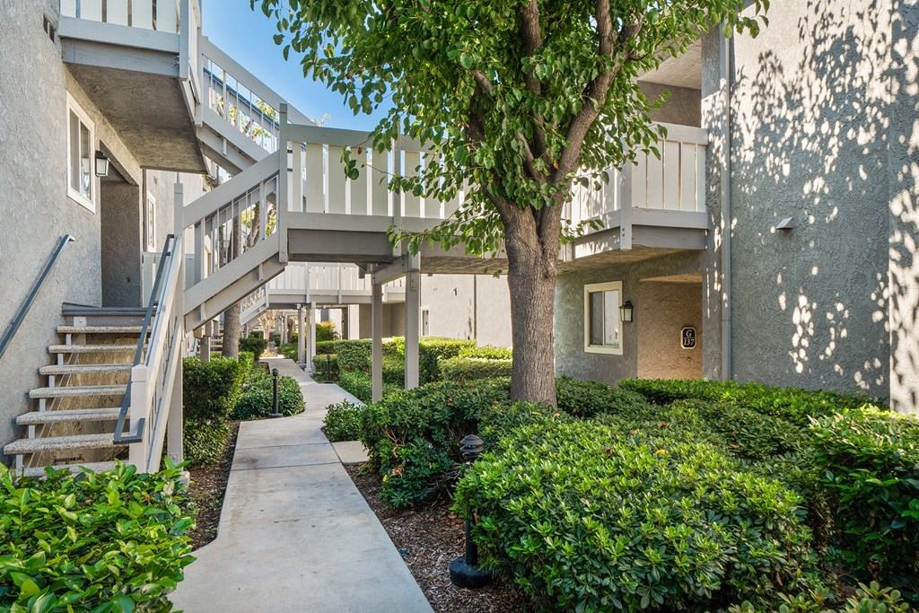 a sidewalk in front of an apartment building with stairs
