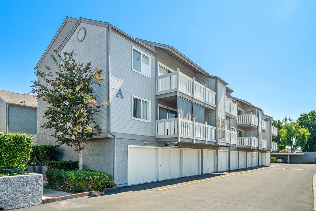 the view of an apartment building with garages and a tree