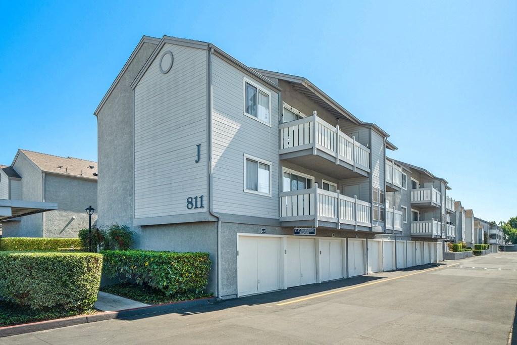 a street view of an apartment building with garages and balconies