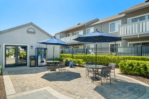 a patio with tables and umbrellas in front of a building