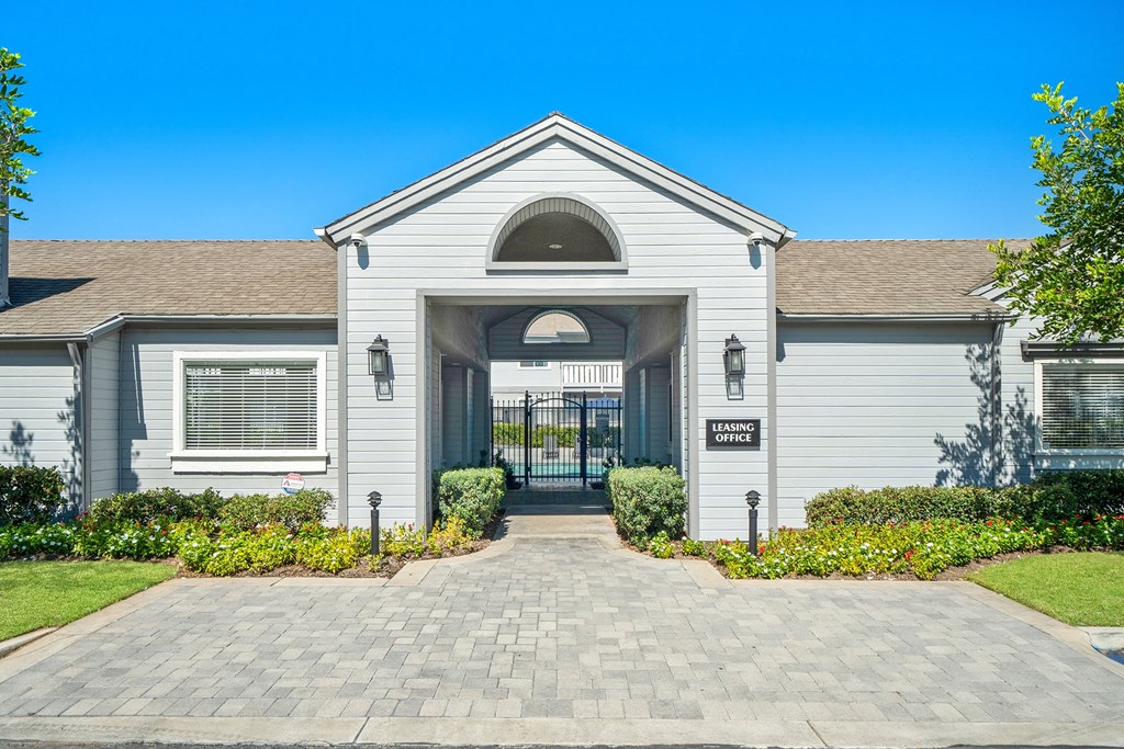 the front of a white house with a driveway and a gate