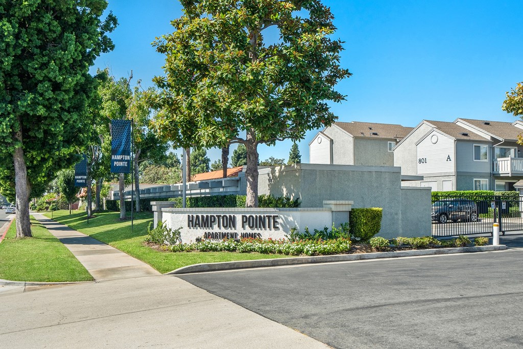 the enclave at harrison pointe apartments sign in front of sidewalk and trees