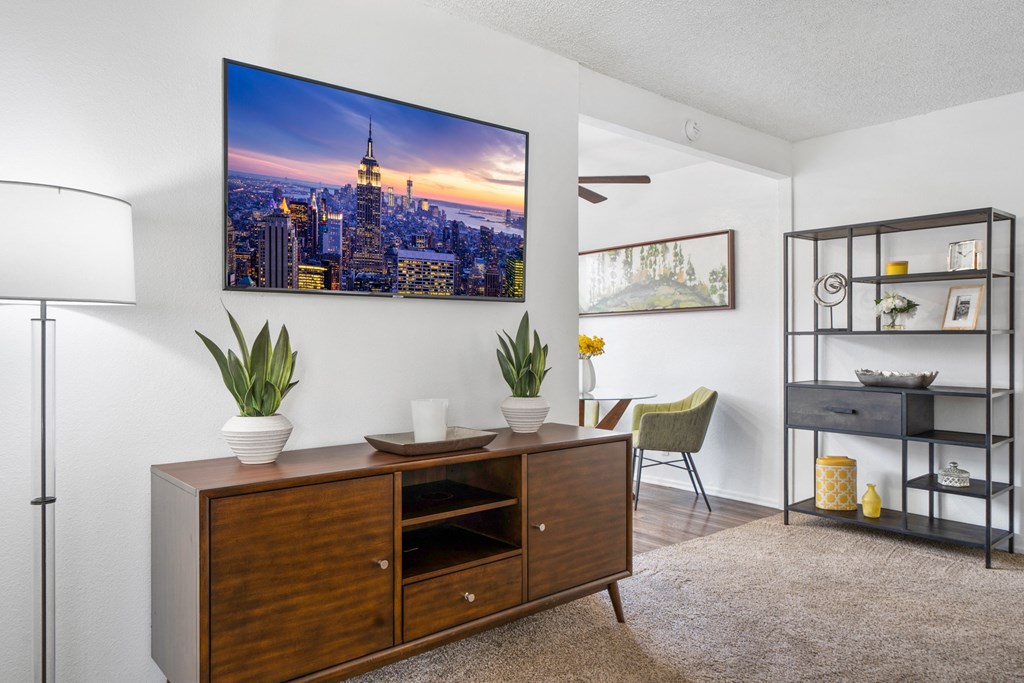 a living room with a desk and a wall mounted picture of a city skyline
