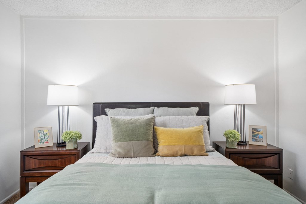 a bedroom with white walls and a bed with green and yellow pillows