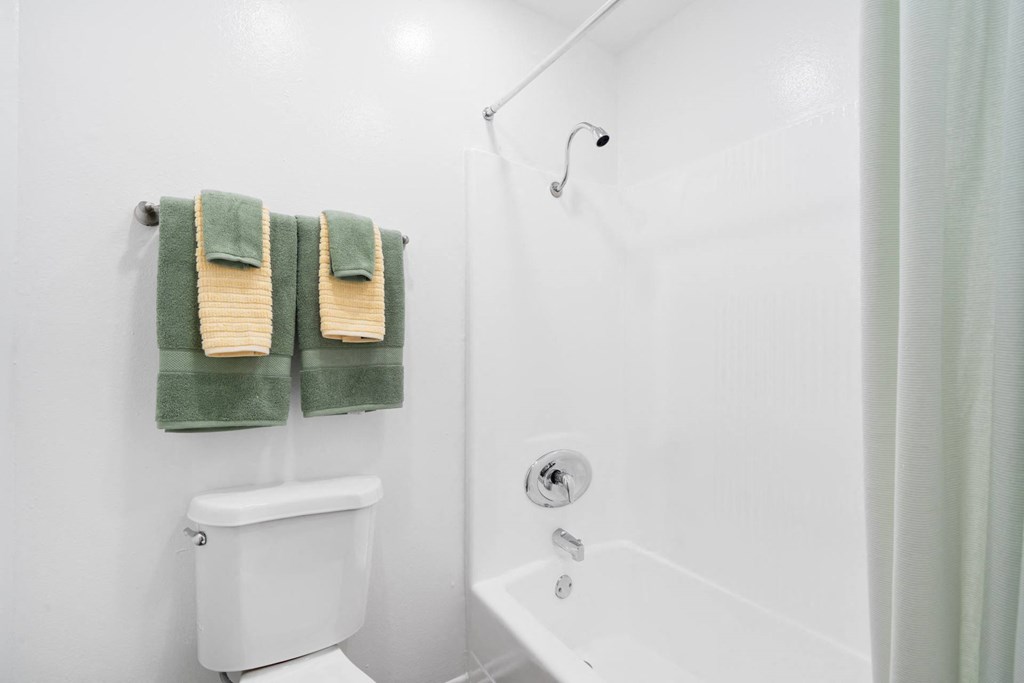 a bathroom with a shower and a toilet and towels