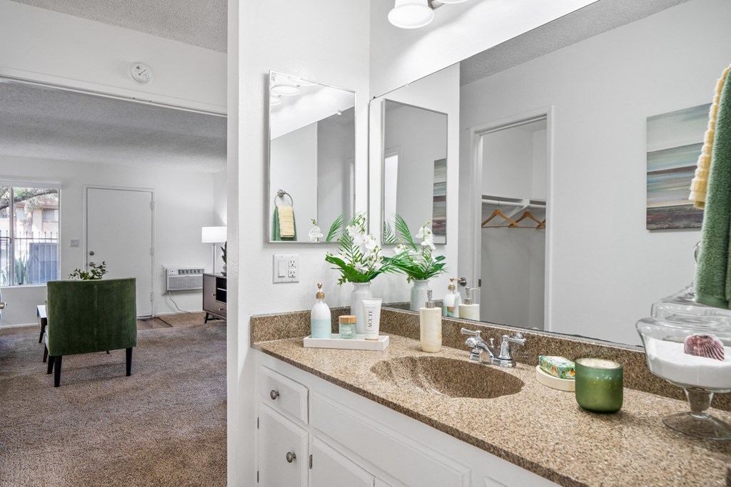 a bathroom with a sink and mirrors and a living room