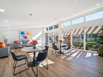 a living room with tables and chairs and large windows