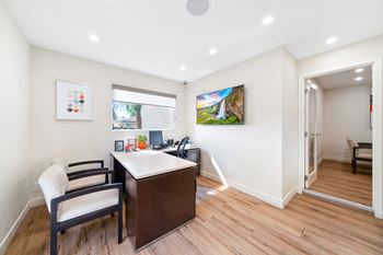 a home office with a desk and chairs and a window