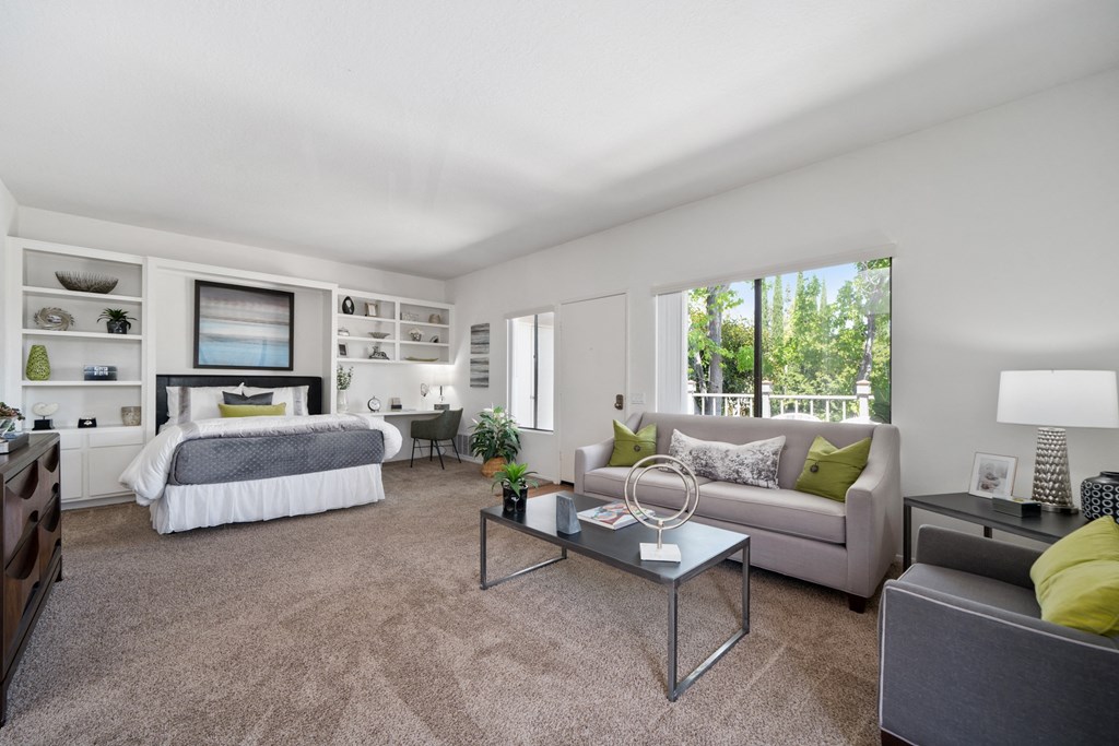 a living room with a couch coffee table and a bed in the background