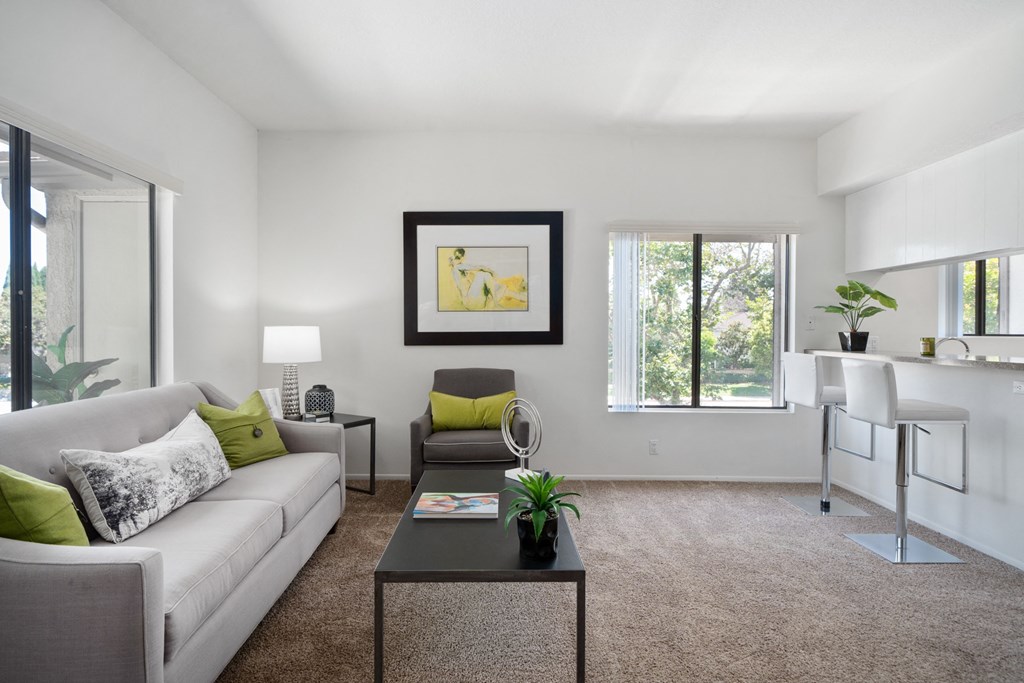 a living room with a couch coffee table and chair and a kitchenette with a bar and