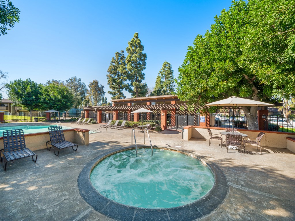 a pool with a hot tub and a patio with tables and chairs