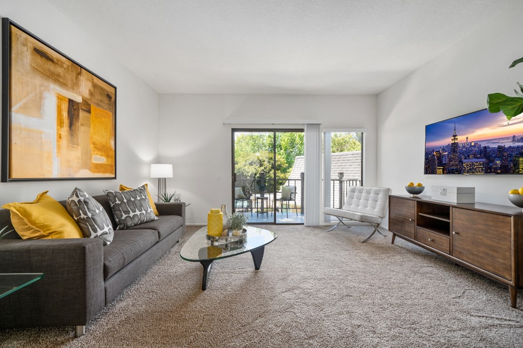 a living room with a couch chair and coffee table with a sliding glass door leading to a