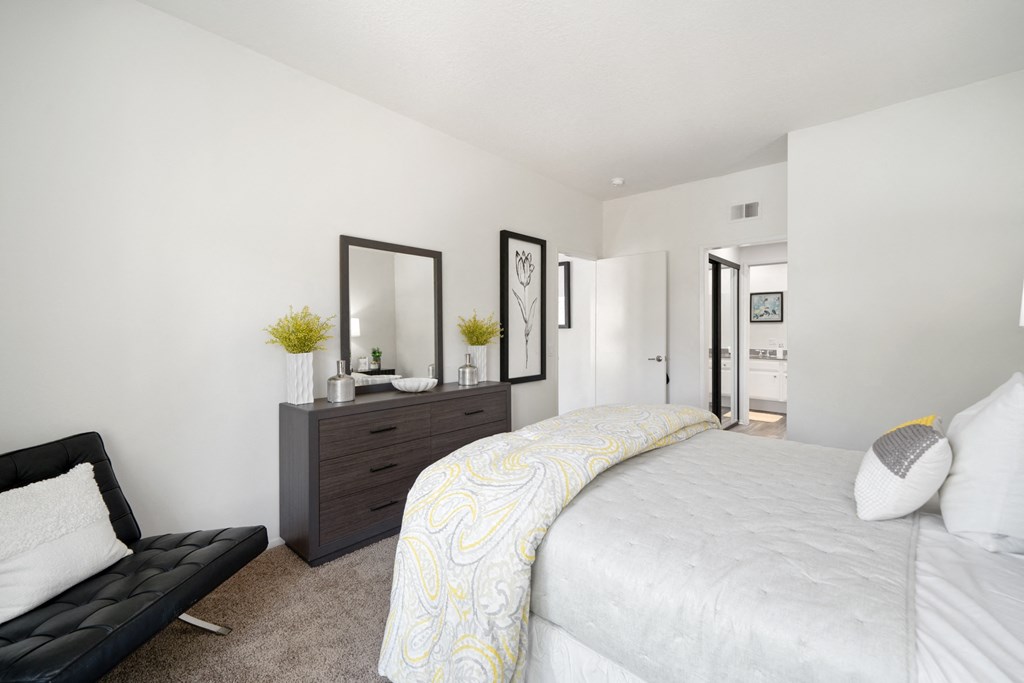 a bedroom with white walls and a large white bed with a yellow and white comforter