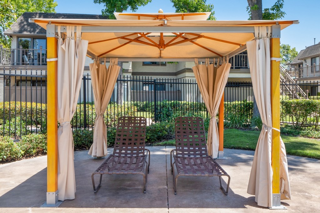 a patio with a gazebo and two chairs