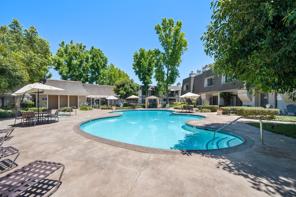 a swimming pool with chairs and umbrellas and a building in the background