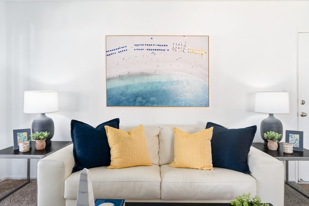 a living room with a white couch and blue pillows