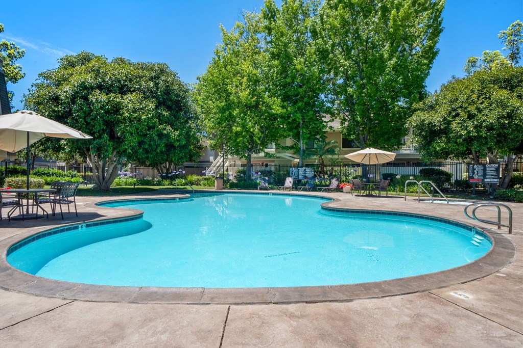 a swimming pool with trees and umbrellas next to a resort style pool