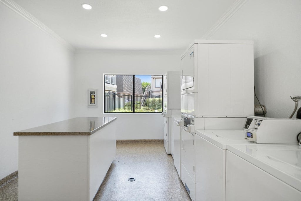 a kitchen with white cabinetry and a large window