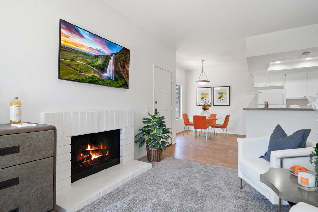 a living room with a fireplace and a dining room in the background