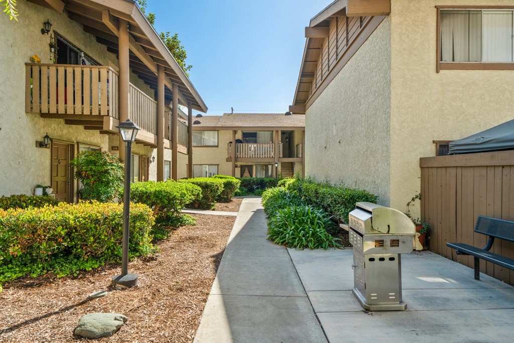 a sidewalk in front of an apartment building with a grill