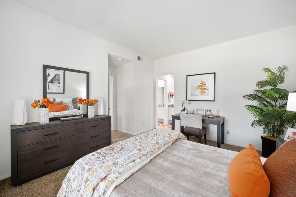 a bedroom with white walls and a large bed with orange pillows