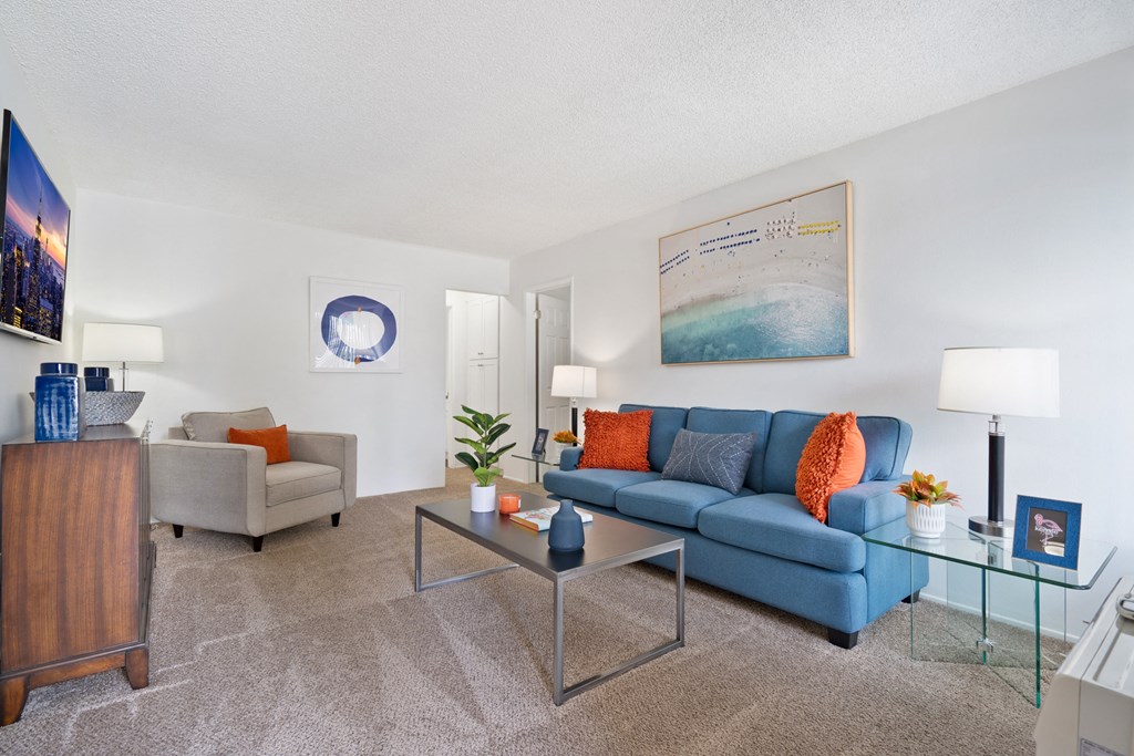 a living room with a blue couch and a glass coffee table
