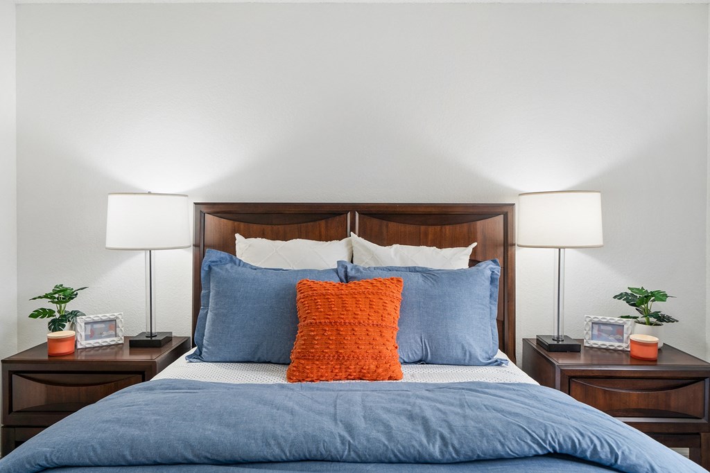 a bedroom with a bed with blue pillows and two nightstands with lamps