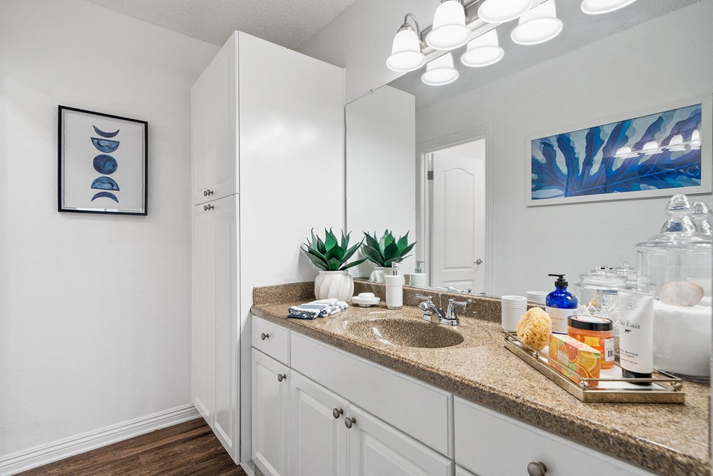 a bathroom with white cabinets and a sink and a mirror