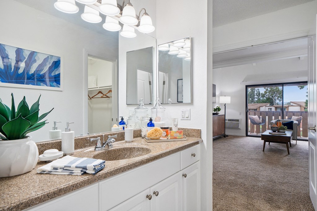 a bathroom with a sink and a mirror and a living room